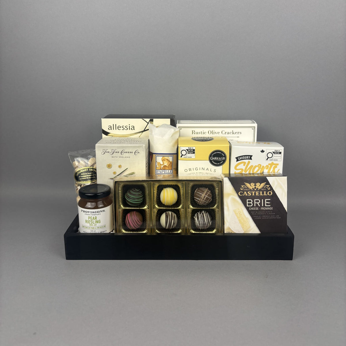 Luxury sweet and savoury gourmet gift basket with Castello Brie cheese, artisan jam, chocolate truffles, and premium snacks displayed on a black serving tray.