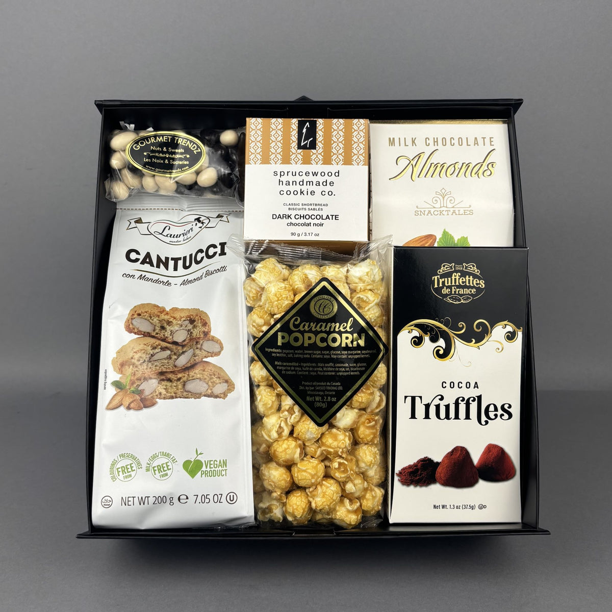 A gourmet chocolate and snack gift box, featuring almond biscotti, Sprucewood Handmade cookies dark chocolate chip, milk chocolate almonds, caramel popcorn, and Chocolate Truffles.