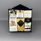A gourmet chocolate and snack gift basket presented in a black container. The basket contains a bag of Cantucci almond biscotti, Sprucewood Handmade Cookies, caramel popcorn, and other assorted sweets. 