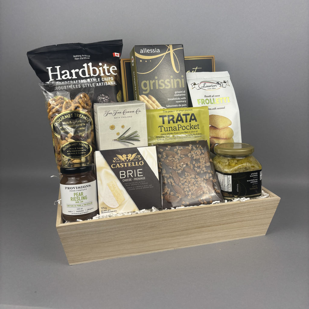 A gourmet gift basket filled with assorted European snacks, cheeses, and crackers, presented in a light wood tray.