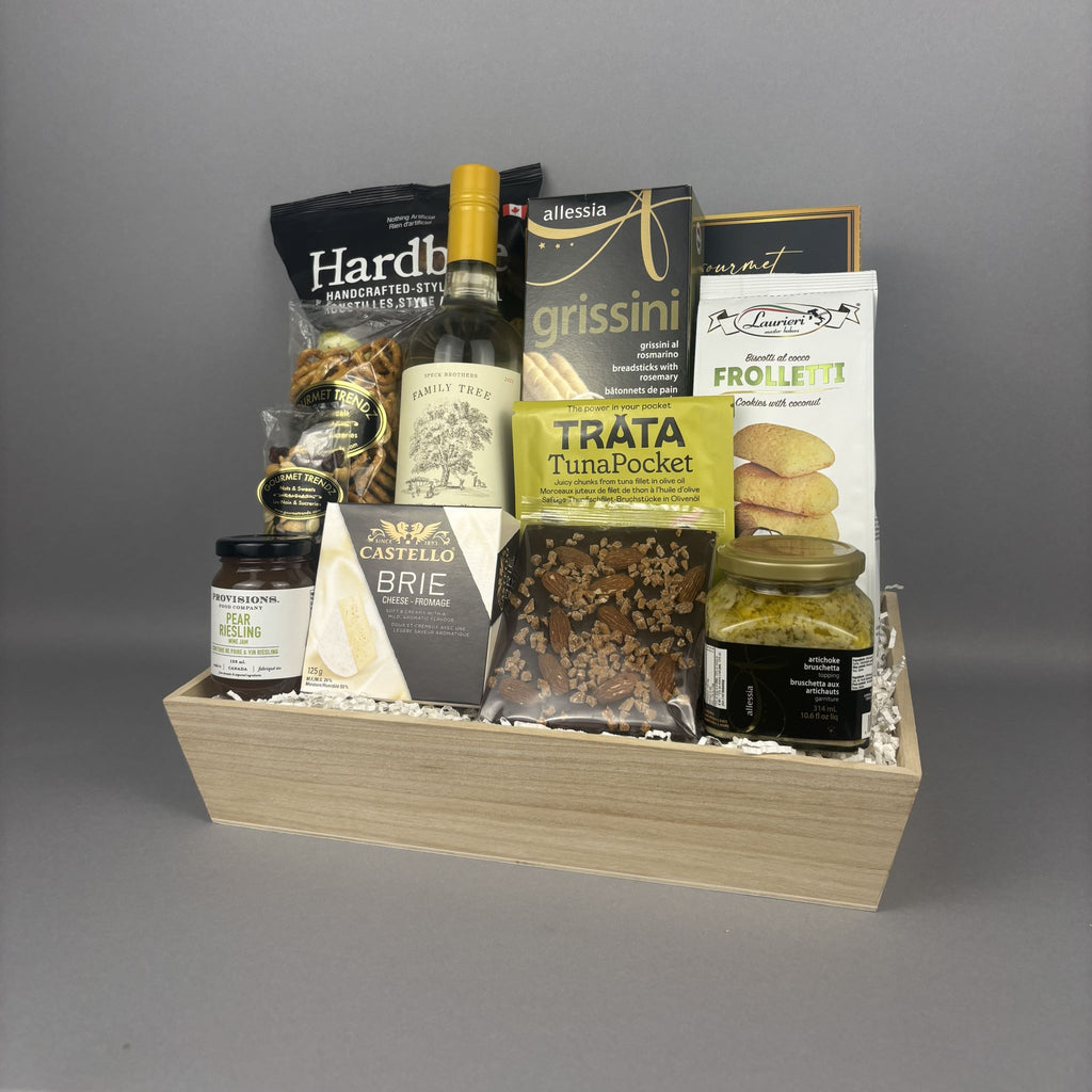 A wooden gift hamper filled with assorted gourmet food items, including a bottle of white wine, cheese, crackers, and jams.