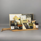 A gourmet gift hamper arranged on a wooden serving board. The hamper includes packaged snacks and foods such as cantucci, Brie cheese, Tràta Salmon Pocket, Aunt Gloria crackers and cookies, and jars of Provsions jams and bruschetta.