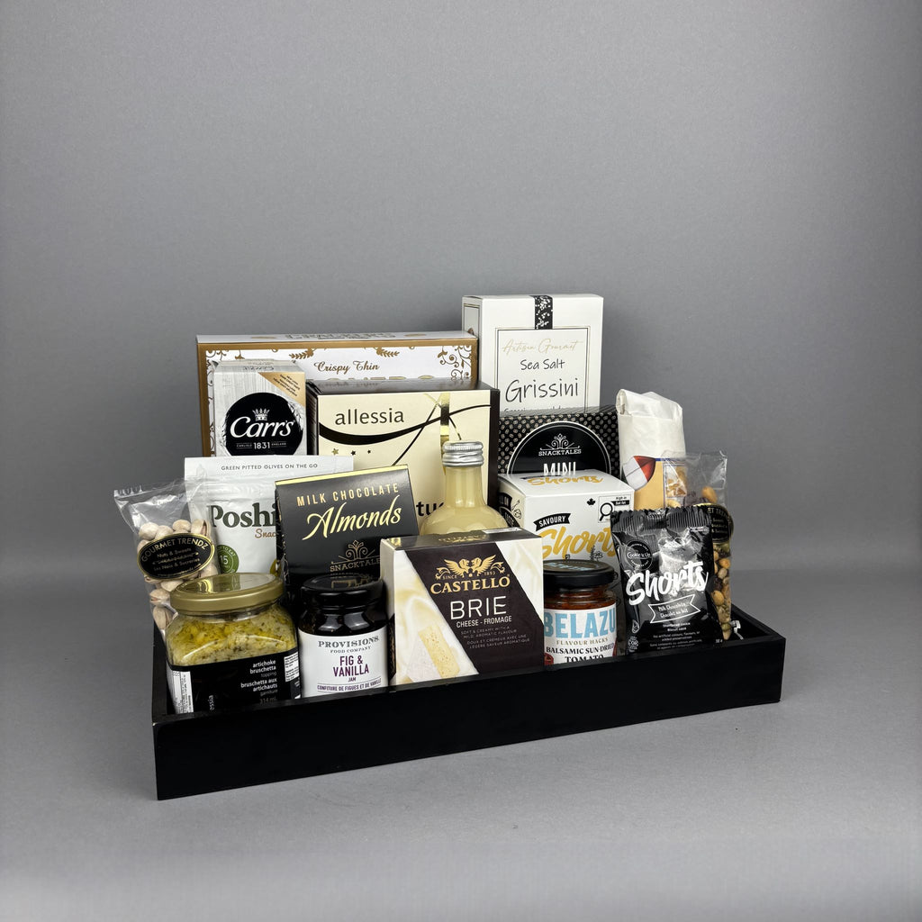A gourmet gift hamper arranged in a black tray, featuring an assortment of cheeses, crackers, nuts, and spreads from brands like Provisions, Allessia, Belazu, and Belberry.
