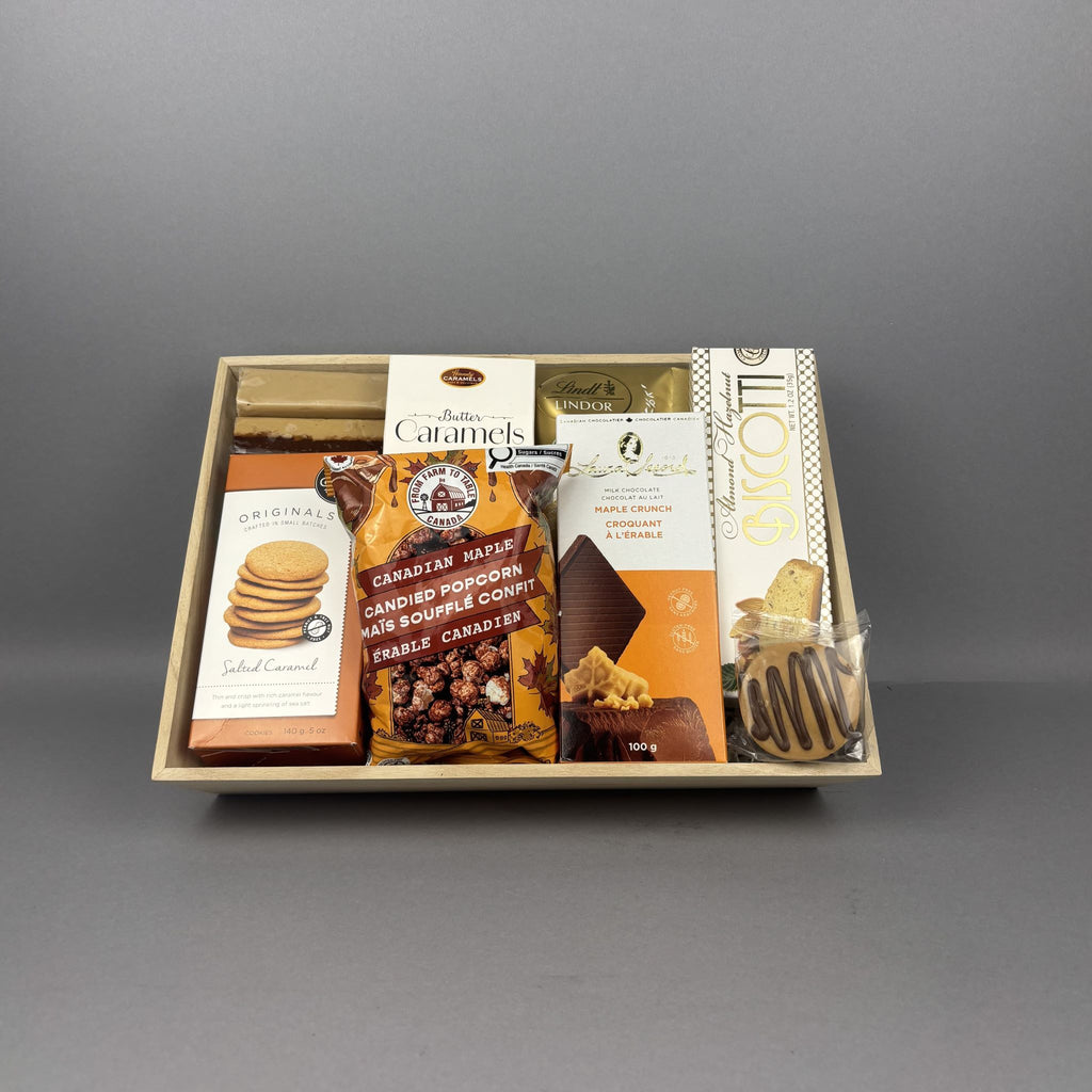 A gourmet chocolate and biscuit gift box containing various packaged treats, including maple fudge, chocolate covered Oreo cookies, Lindt chocolates, biscotti, and other decadent treats.