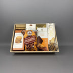 A gourmet chocolate and biscuit gift box containing various packaged treats, including maple fudge, chocolate covered Oreo cookies, Lindt chocolates, biscotti, and other decadent treats.
