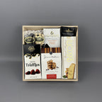 A gourmet chocolate and biscuit gift box set in a light wood tray, featuring Truffettes de France cocoa truffles, J&M chocolate chip cookies, and a luxury almond biscotti box, Laura Secord chocolate bar and fudge.