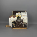 A chocolate gift basket arranged on a wooden tray. The basket contains assorted chocolates, including a bag of Cantucci, milk chocolate almonds, a bag of chocolate-covered raisins , and other packaged sweets.