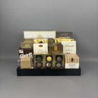 A gourmet chocolate and snack gift basket arranged on a black tray. The assortment includes milk chocolate almonds, shortbread cookies, caramel candies, and various boxed chocolates from brands like Made Chocolate and Andea Chocolates.