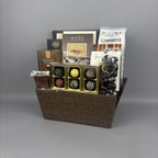 A gourmet chocolate gift basket in a brown woven basket, filled with assorted chocolates, truffles, and chocolate bars including Old English Fudge and Made Chocolates.