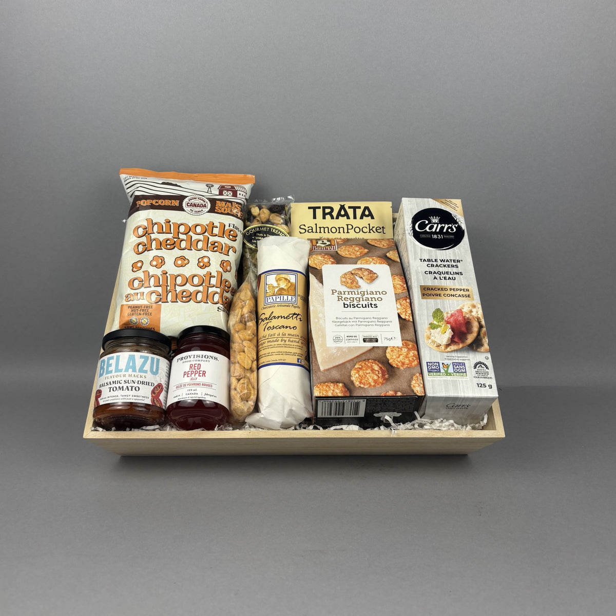 Gourmet gift crate with premium snacks, smoked salmon, chipotle cheddar popcorn, artisan crackers, provisions jam, savory spreads, and specialty foods in a wooden tray.